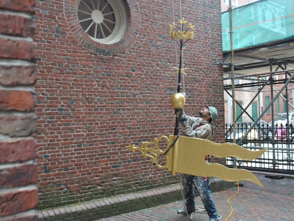 The weathervane being reinstalled after maintenance work on the steeple.