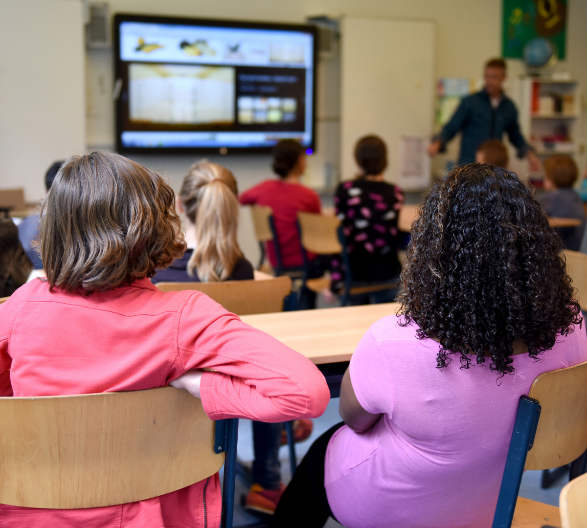 Children watching their teacher in a classroom.